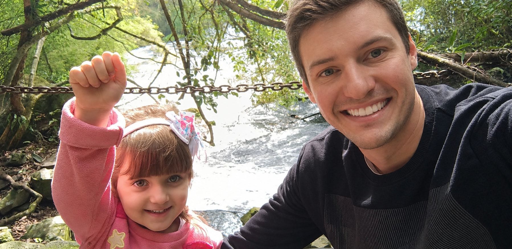 Raphael and his daughter smiling in front of a waterfall